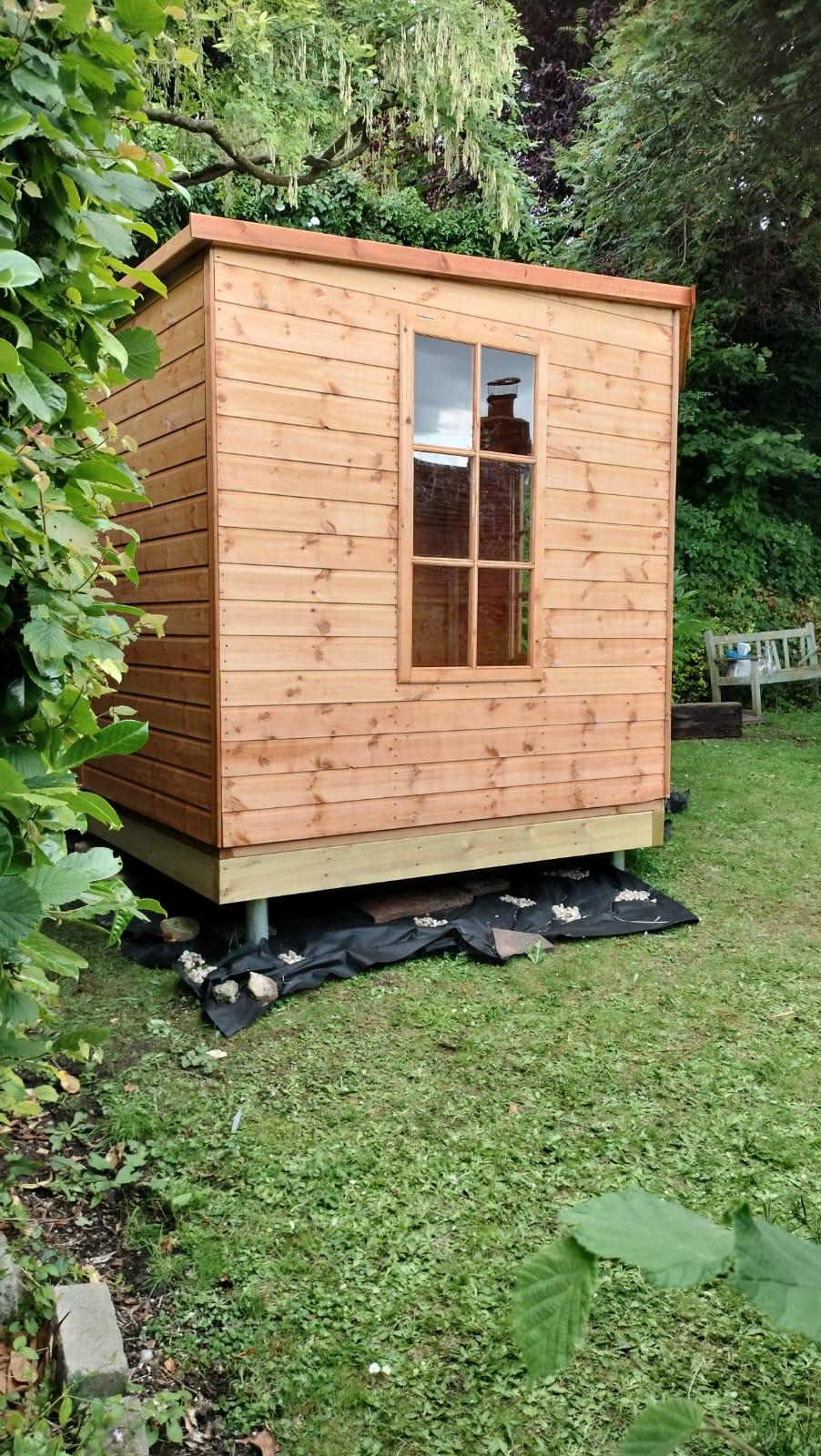 Finished shed on sloped ground installed level by Gorilla Base on ground screws